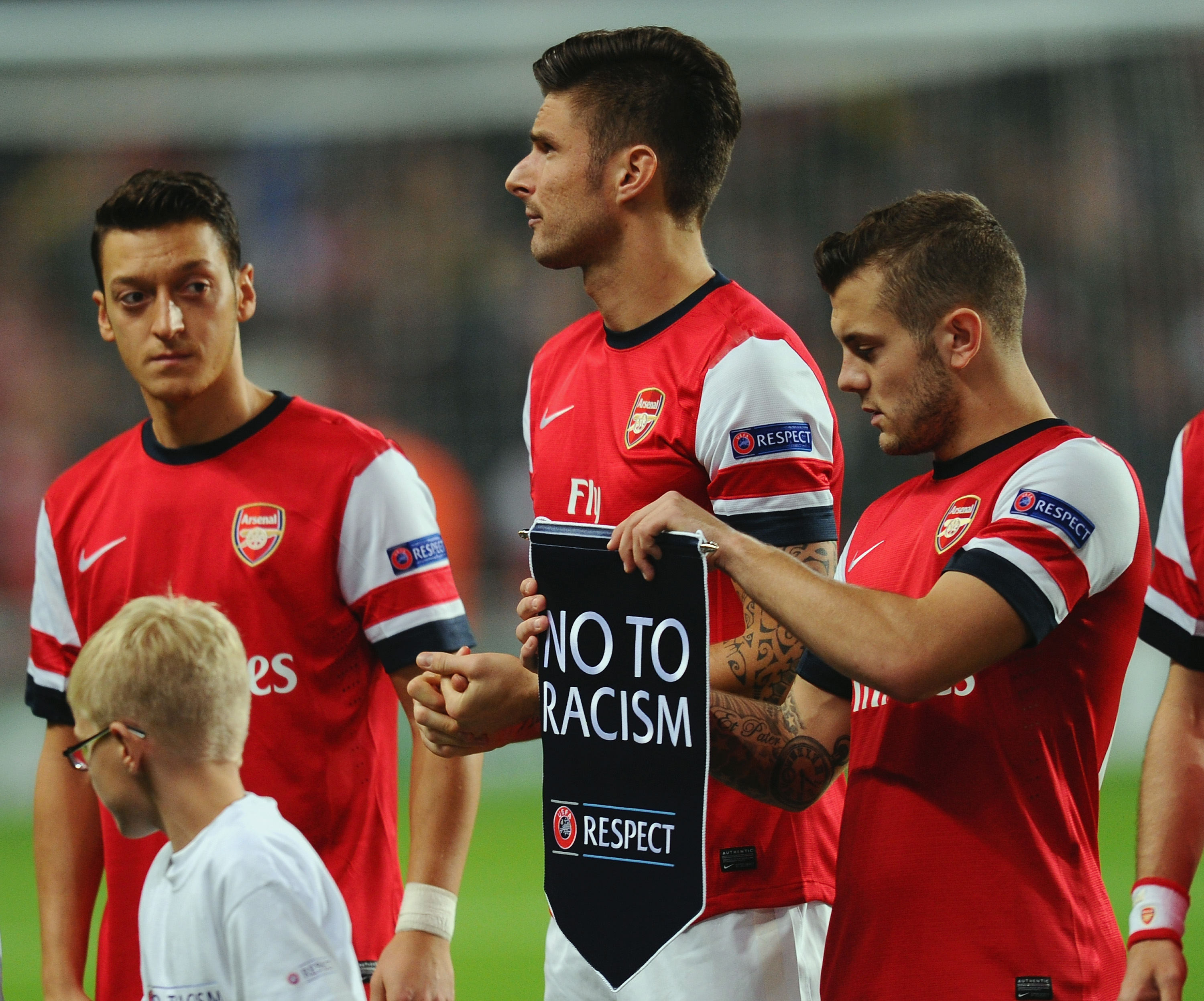 LONDON, ENGLAND - OCTOBER 22: Jack Wilshere of Arsenal prepares to hand the 'No to Racism' pennant to Olivier Giroud of Arsenal during the UEFA Champions League Group F match between Arsenal and  Borussia Dortmund at Emirates Stadium on October 22, 2013 in London, England.  (Photo by Mike Hewitt/Bongarts/Getty Images)