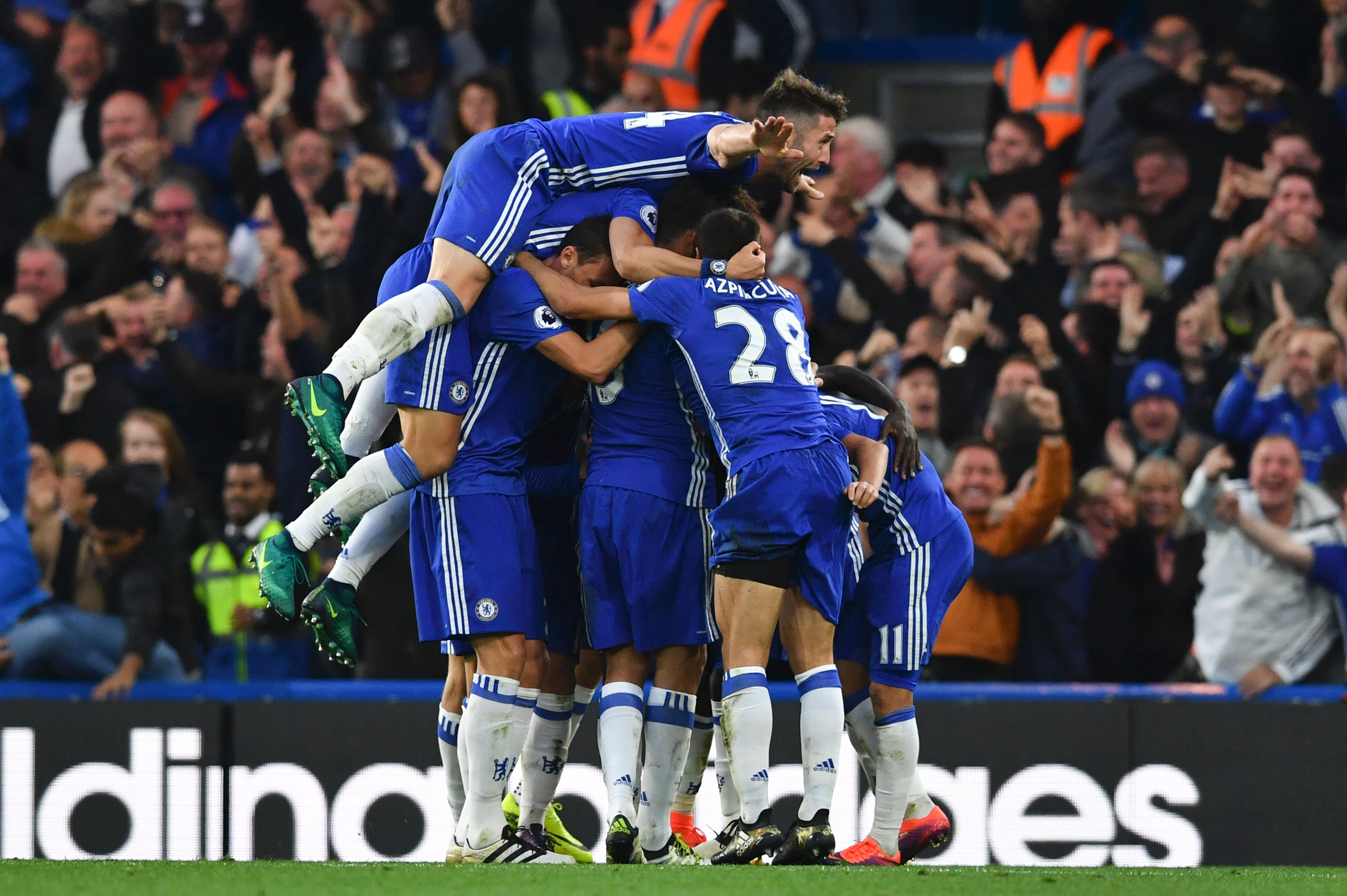 Chelsea's English defender Gary Cahill (top) jumps onto the huddle to join the celebrates after Chelsea's French midfielder N'Golo Kante scored their fourth goal during the English Premier League football match between Chelsea and Manchester United at Stamford Bridge in London on October 23, 2016. / AFP / BEN STANSALL / RESTRICTED TO EDITORIAL USE. No use with unauthorized audio, video, data, fixture lists, club/league logos or 'live' services. Online in-match use limited to 75 images, no video emulation. No use in betting, games or single club/league/player publications. / (Photo credit should read BEN STANSALL/AFP/Getty Images)
