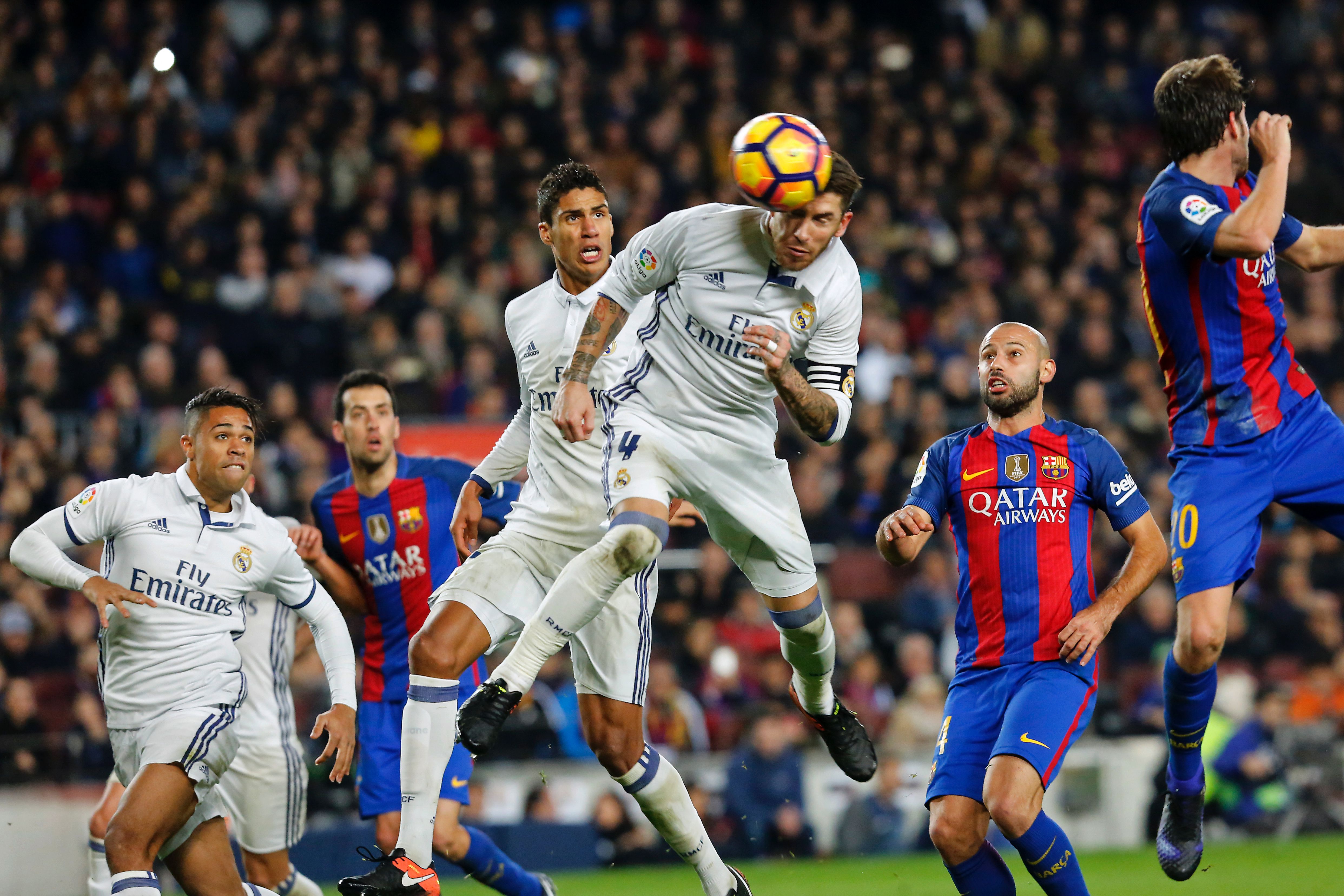 TOPSHOT - Real Madrid's defender Sergio Ramos (C) heads a ball to score the equalizer past Real Madrid's French defender Raphael Varane (3rdL) and Barcelona's Argentinian defender Javier Mascherano (R) during the Spanish league football match FC Barcelona vs Real Madrid CF at the Camp Nou stadium in Barcelona on December 3, 2016. / AFP / PAU BARRENA (Photo credit should read PAU BARRENA/AFP/Getty Images)