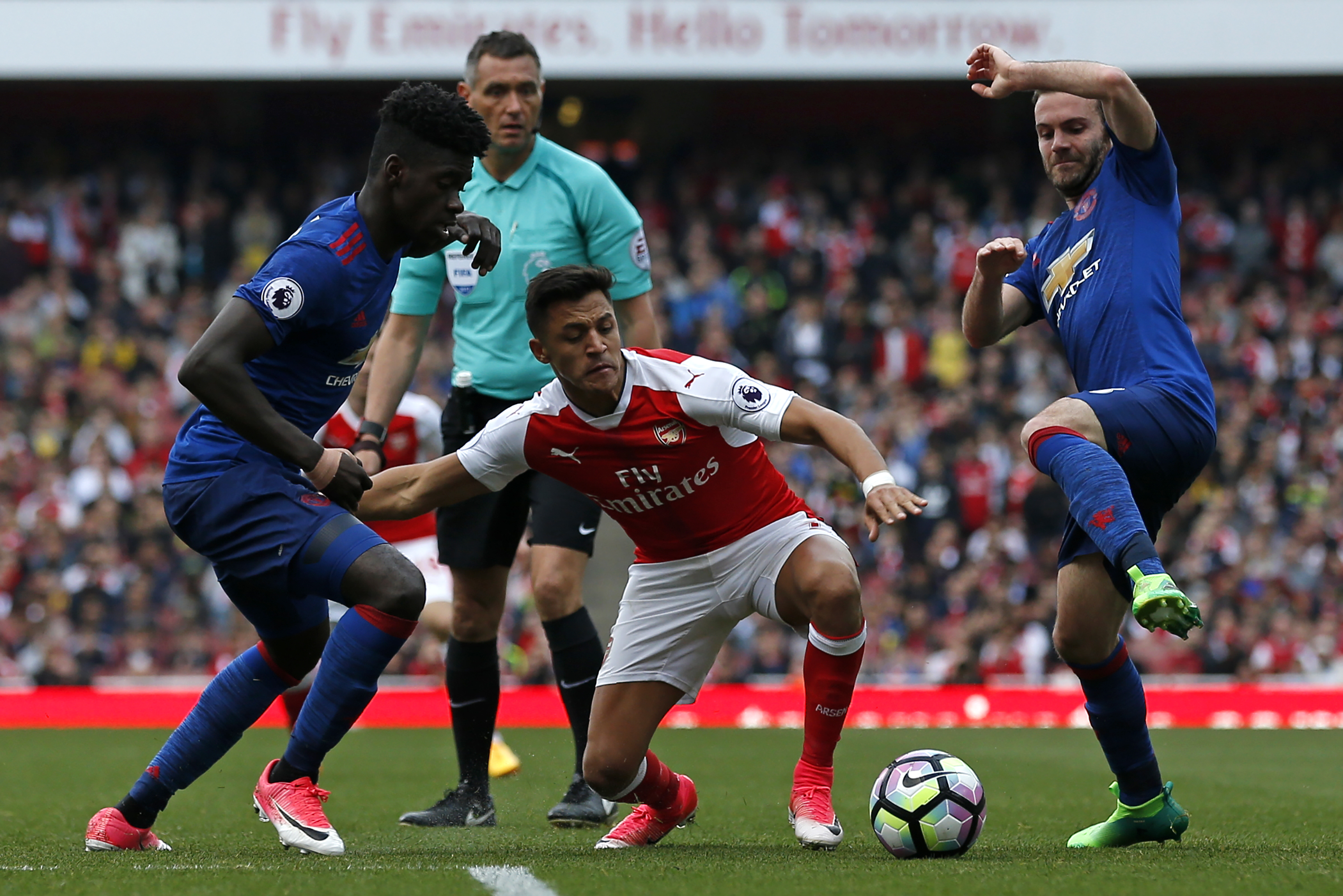 Arsenal's Chilean striker Alexis Sanchez (C) vies with Manchester United's DR Congo-born defender Axel Tuanzebe (L) and Manchester United's Spanish midfielder Juan Mata (R) during the English Premier League football match between Arsenal and Manchester United at the Emirates Stadium in London on May 7, 2017. 
Arsenal won the game 2-0. / AFP PHOTO / IKIMAGES / Ian KINGTON / RESTRICTED TO EDITORIAL USE. No use with unauthorized audio, video, data, fixture lists, club/league logos or 'live' services. Online in-match use limited to 45 images, no video emulation. No use in betting, games or single club/league/player publications.  /         (Photo credit should read IAN KINGTON/AFP/Getty Images)