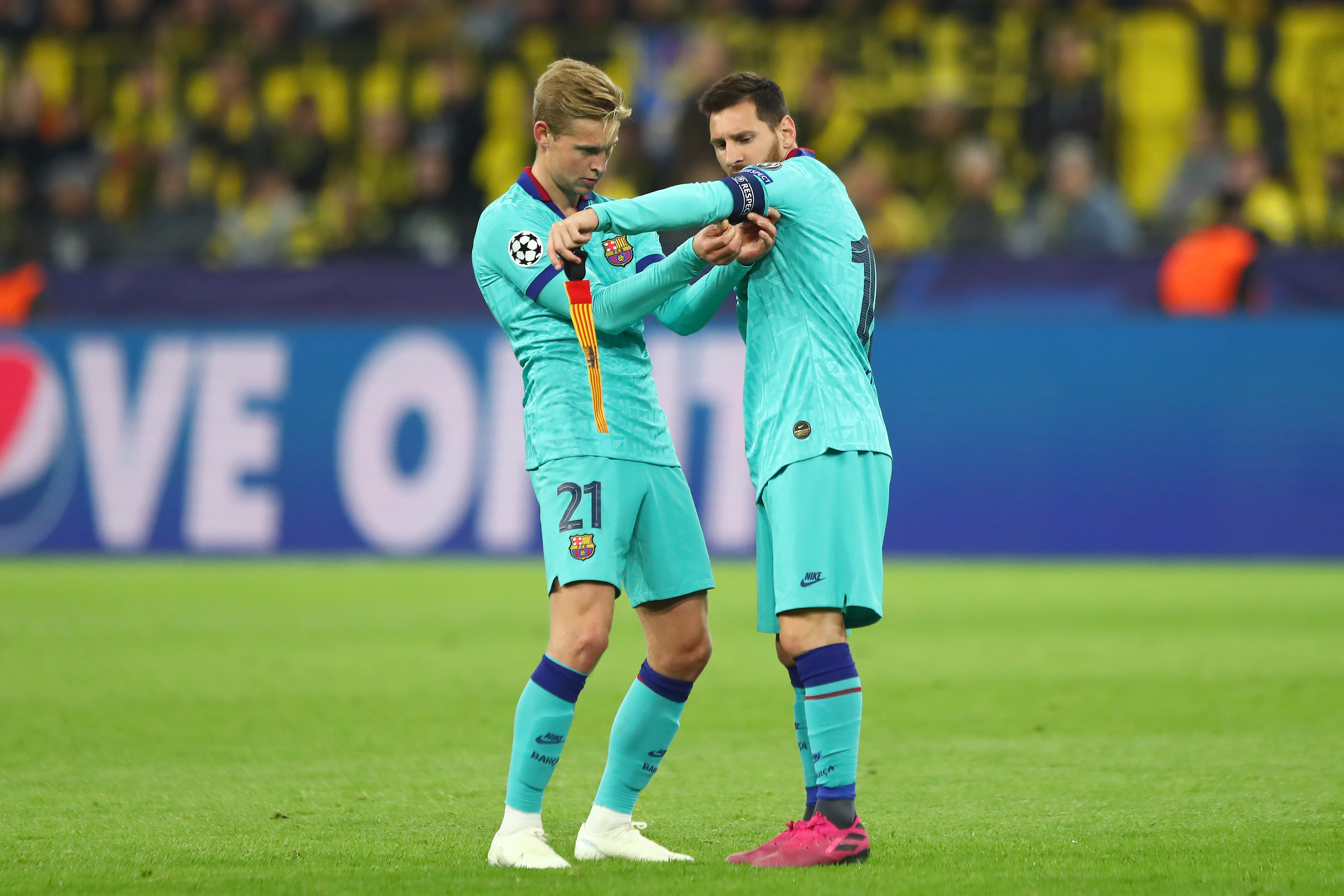 DORTMUND, GERMANY - SEPTEMBER 17:  Frenkie de Jong of FC Barcelona assists Lionel Messi with the captain's armband during the UEFA Champions League group F match between Borussia Dortmund and FC Barcelona at Signal Iduna Park on September 17, 2019 in Dortmund, Germany. (Photo by Martin Rose/Bongarts/Getty Images)